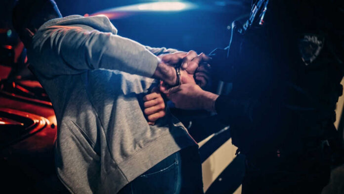Police officer arresting a person at night.