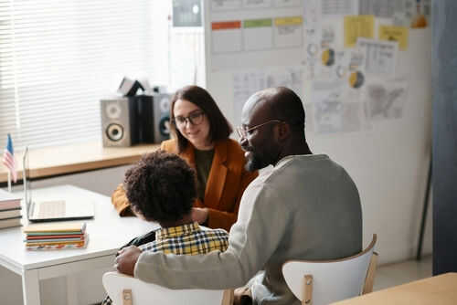 Three people sitting at a desk talking together