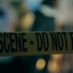 Fake DEA Badges, Missing Women—What’s Hiding Here? Caution tape marking a crime scene with blurred figures in the background