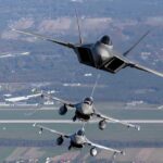 Three military fighter jets flying in formation above a landscape
