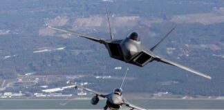 Three military fighter jets flying in formation above a landscape