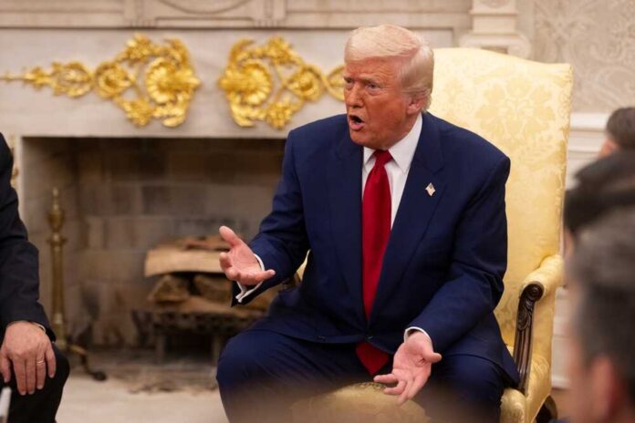 A man in a blue suit and red tie gesturing during a discussion in a formal setting