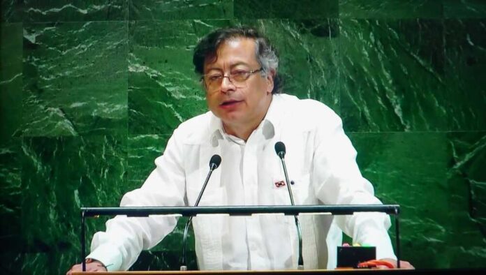 A speaker in a white shirt addressing an audience at a podium