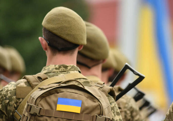 ukraine-troops-498563046 Soldiers with backpacks and Ukrainian flags in formation