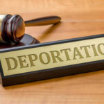 Trump Shirt Fight Ends In Deportation Case Gavel and sign reading Deportation on desk.