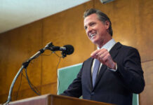 Federal Corruption Probe Roils Newsom’s Inner Circle Man speaking at podium with microphone