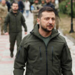Ukraine’s Biggest Shake-Up Raises Hard Questions Zelensky walking outdoors with military personnel nearby.