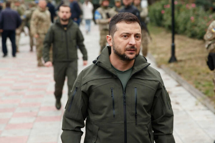 presidentialhill2-1jpg Zelensky walking outdoors with military personnel nearby.