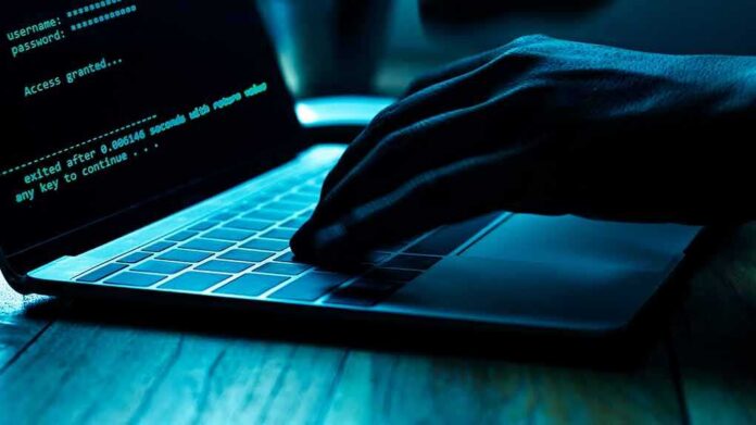 Hand typing on laptop with green code on screen