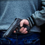 Person holding a handgun behind their back