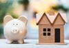 What’s Really Behind Sky-High Home Prices? Piggy bank beside cardboard house model on a table