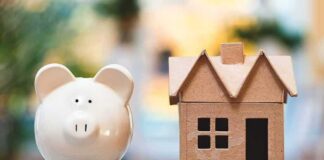 Piggy bank beside cardboard house model on a table