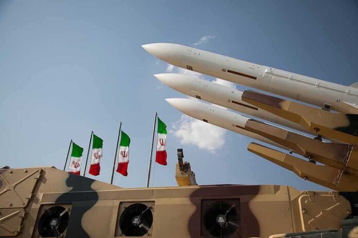 Missile launchers on a military vehicle with flags in the background