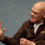 Bald man speaking into a handheld microphone