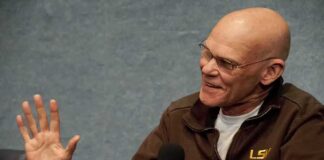 Bald man speaking into a handheld microphone