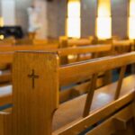 Wooden church pew with carved cross in a sunlit sanctuary