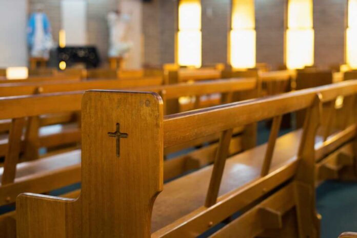 Wooden church pew with carved cross in a sunlit sanctuary