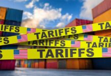 Yellow caution tape with the word 'TARIFFS' over a background of shipping containers