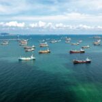 What Triggered America’s Massive Response? Aerial view of numerous cargo ships anchored in a blue ocean