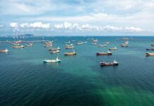 What Triggered America’s Massive Response? Aerial view of numerous cargo ships anchored in a blue ocean