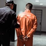 Death Row Countdown: Three at Once Police officer escorting handcuffed inmate in orange jumpsuit