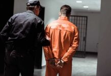 Police officer escorting handcuffed inmate in orange jumpsuit