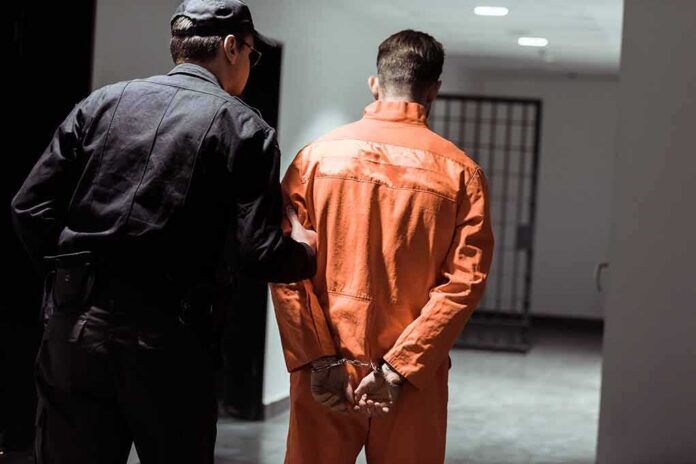 Police officer escorting handcuffed inmate in orange jumpsuit
