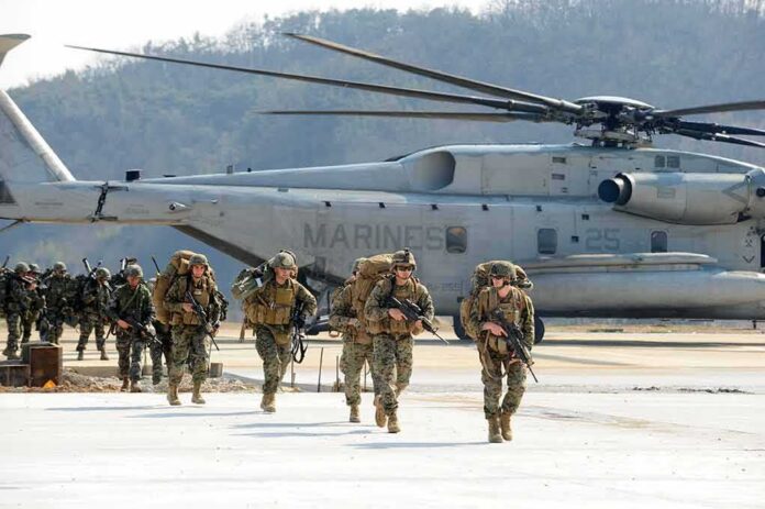 Soldiers disembark and walk past a large military helicopter