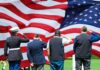 Veterans salute a large American flag