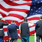 Veterans salute a large American flag