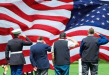 Veterans salute a large American flag