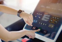 Person using a treadmill touchscreen with a smartwatch