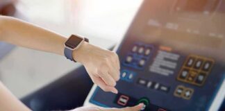 Person using a treadmill touchscreen with a smartwatch