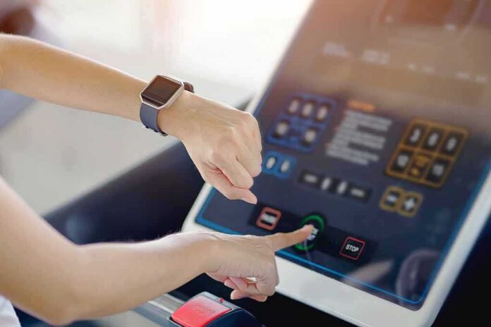 Person using a treadmill touchscreen with a smartwatch