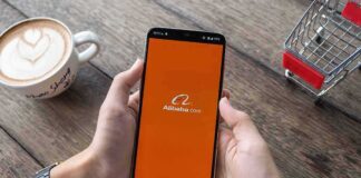 Person holding smartphone with Alibaba app on screen