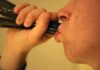 Person drinking from a dark bottle close-up