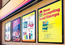 Store window posters advertising SNAP EBT acceptance and product deals