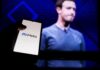 smartphone showing Meta logo in front of a blurred speaker on stage