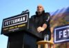 Speaker at outdoor rally standing at podium with microphone