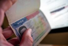 A Sweeping Visa Reset Is Now Underway Hand holding a passport with a visa page