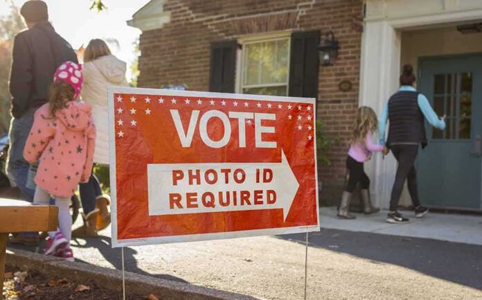 Red voting sign with arrow near people entering a polling place