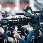 Transit Crash Probe Points To One Human Failure Broadcast cameras on tripods at a press event