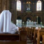 Faith Showdown: Nuns vs. Suicide Mandate Person in white habit seated in a church pew facing the altar