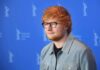 Ed Sheeran posing at a photo call against a blue backdrop