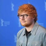 Ed Sheeran posing at a photo call against a blue backdrop