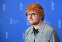 Ed Sheeran posing at a photo call against a blue backdrop