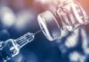 syringe needle drawing liquid from a vaccine vial