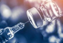 syringe needle drawing liquid from a vaccine vial