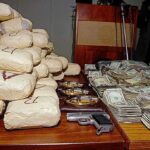 Seized packages, cash, and handguns on a table