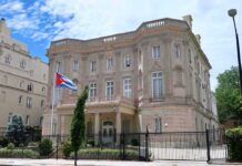 neoclassical stone building with a Cuban flag and iron fence